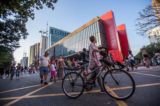 A man is riding a bike down a street in front of a building.
