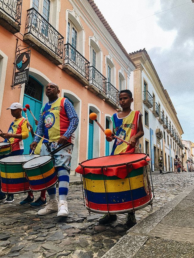 A group of people playing drums on a cobblestone street