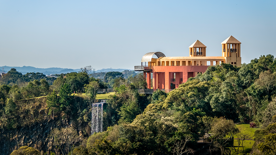 A large building is sitting on top of a hill surrounded by trees.