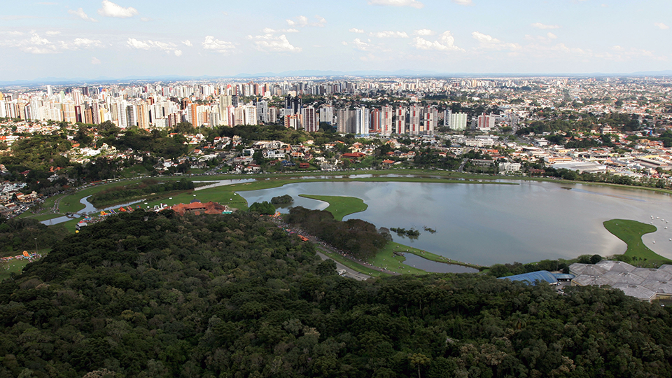 An aerial view of a lake surrounded by trees and a city.