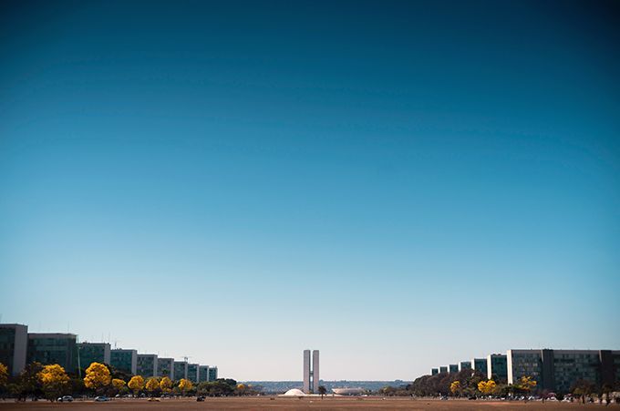 A large building with a blue sky in the background is surrounded by trees and buildings.
