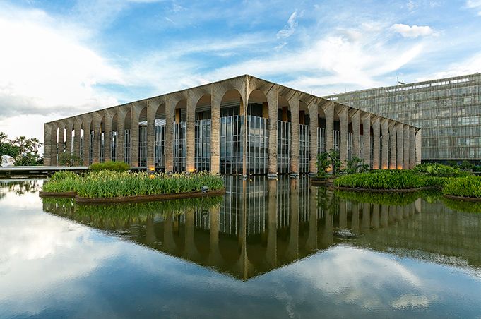 A large building with arches is reflected in the water.