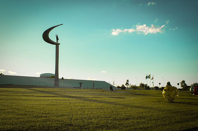 A statue of a crescent moon is in the middle of a grassy field.