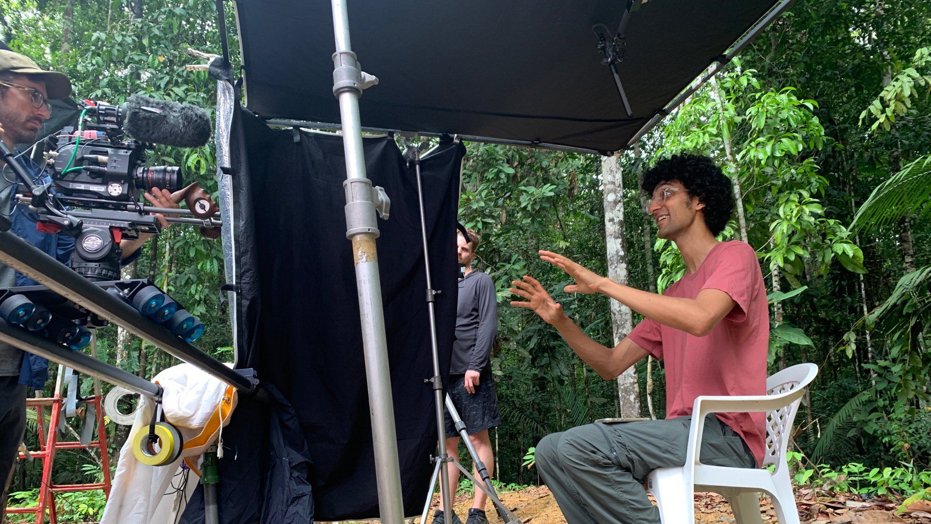 A man is sitting in a chair in front of a camera.