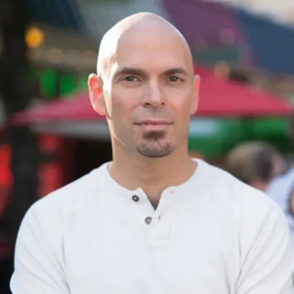 A bald man with a beard is wearing a white shirt