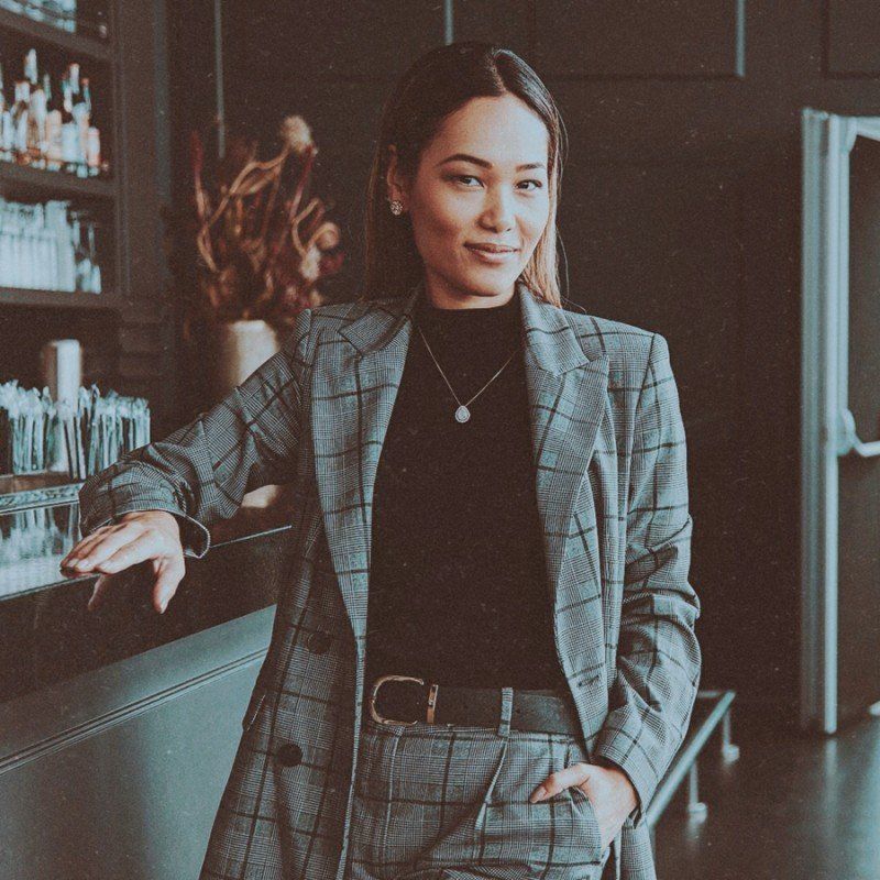A woman in a suit is standing in front of a bar