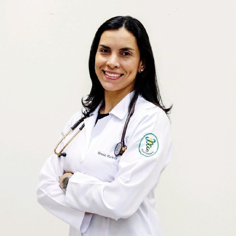 A woman in a white lab coat with a stethoscope around her neck is smiling.