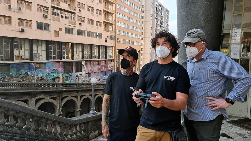 Three men looking up to a drone shooting