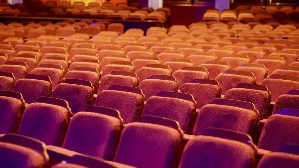 Rows of purple and orange seats in an auditorium.