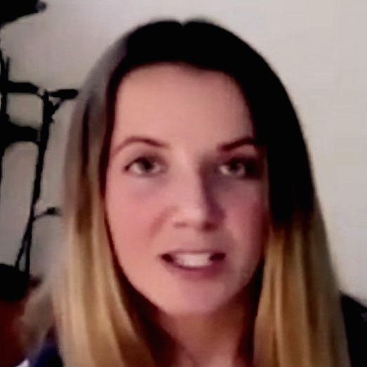 A woman with long blonde hair is smiling and looking at the camera.