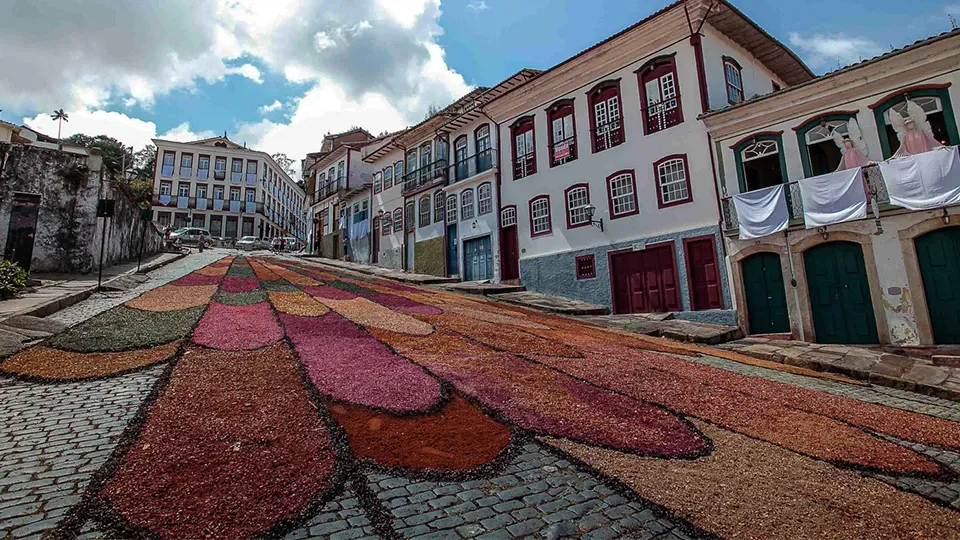 There is a carpet of flowers on the sidewalk in front of a building.