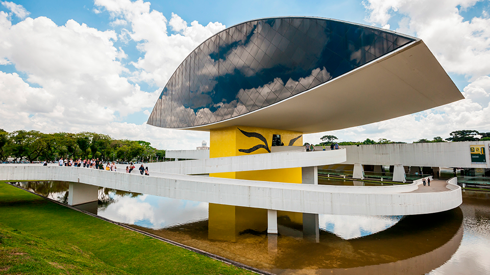 A large building with a curved roof is next to a body of water.