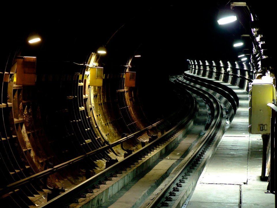 A train track in a dark tunnel with lights on