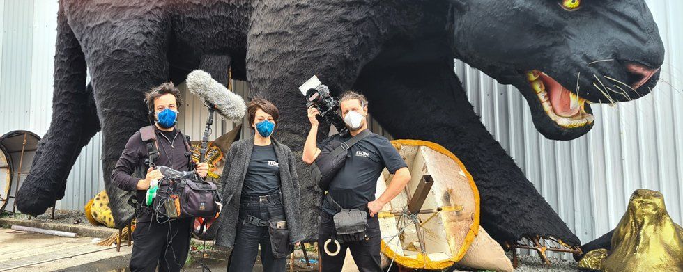 A group of people wearing masks are standing in front of a statue of a black panther.