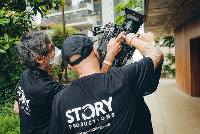 Two men are standing next to each other holding a camera.