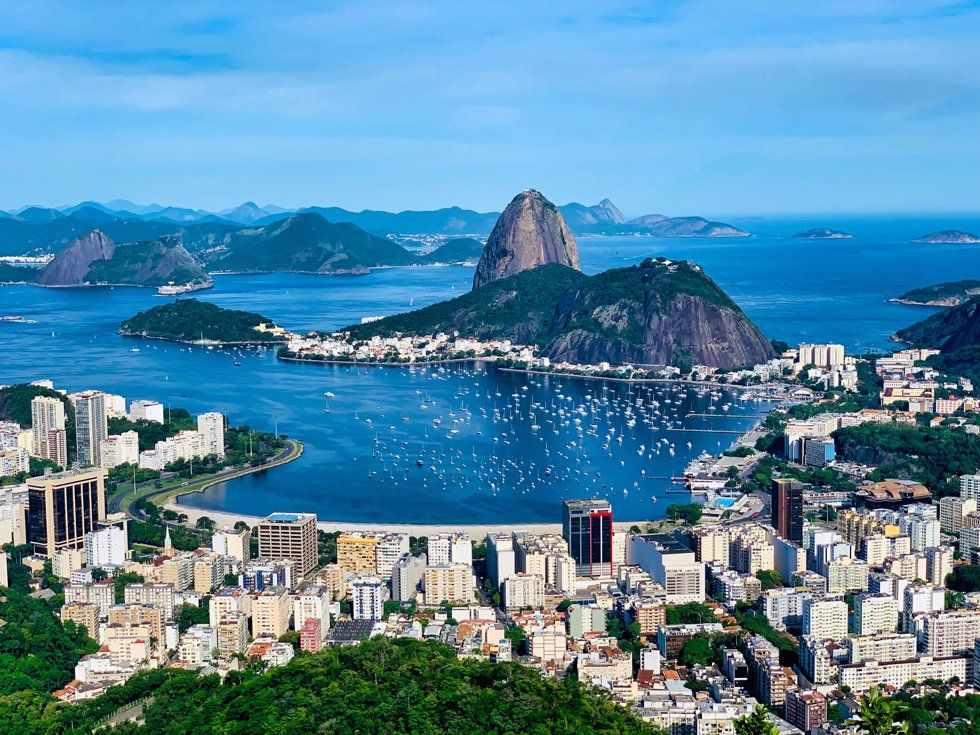An aerial view of rio de janeiro with mountains in the background and a city in the foreground.