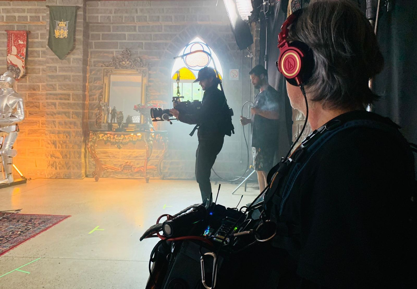 A man wearing headphones is standing in front of a camera.