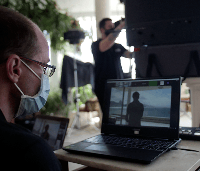 A man wearing a mask looks at a laptop screen