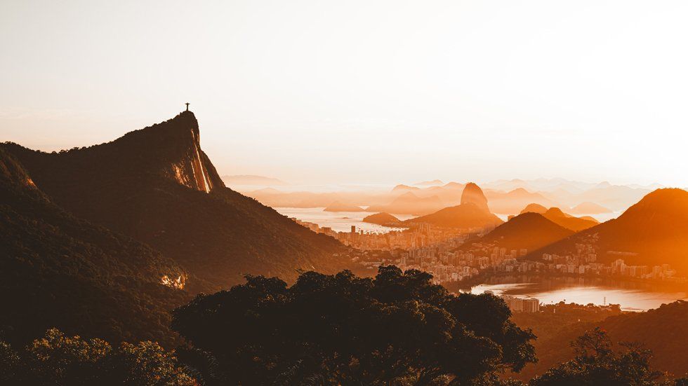 A view of a city from the top of a mountain at sunset.