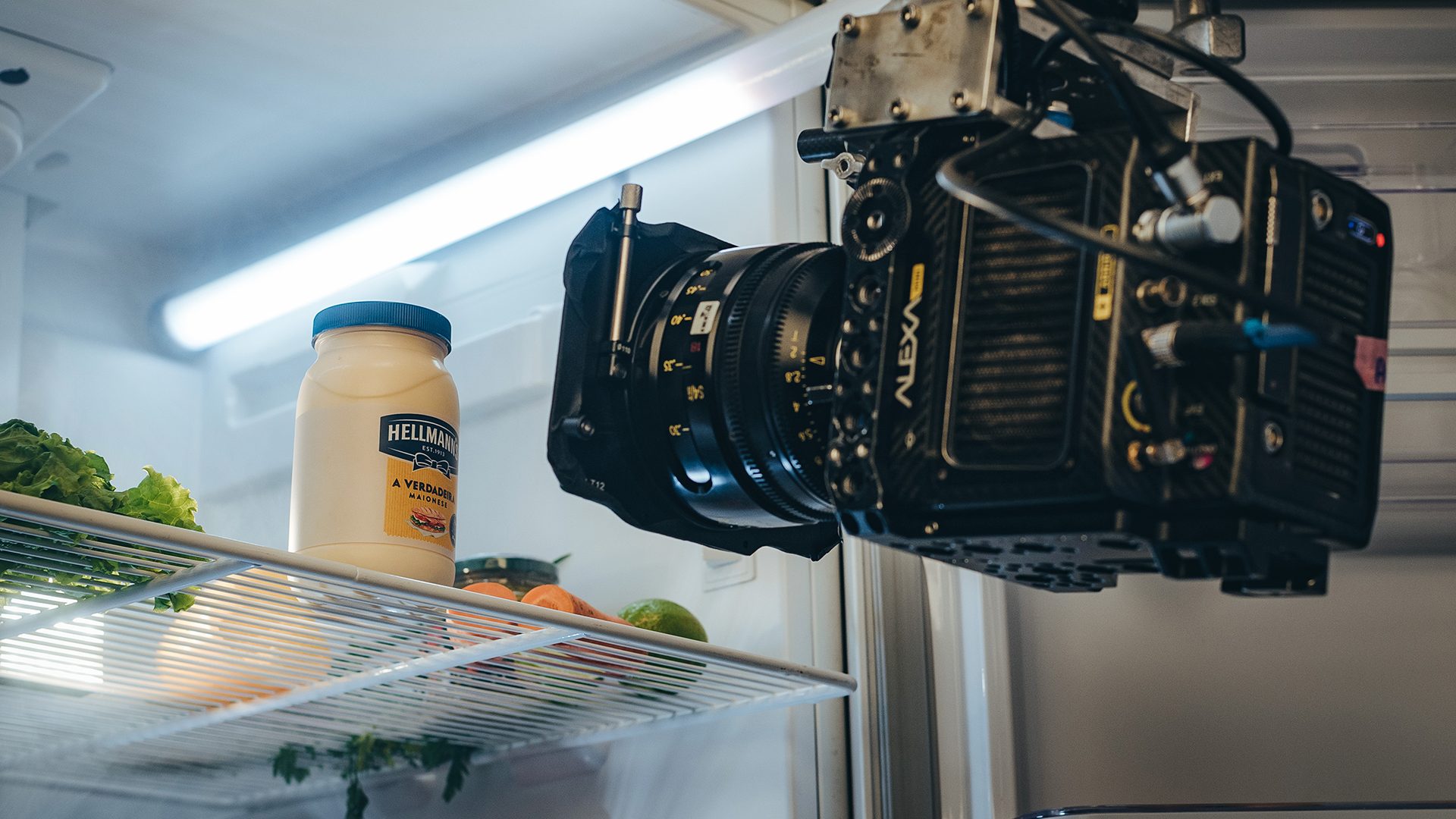 A camera is hanging from the ceiling of a refrigerator.