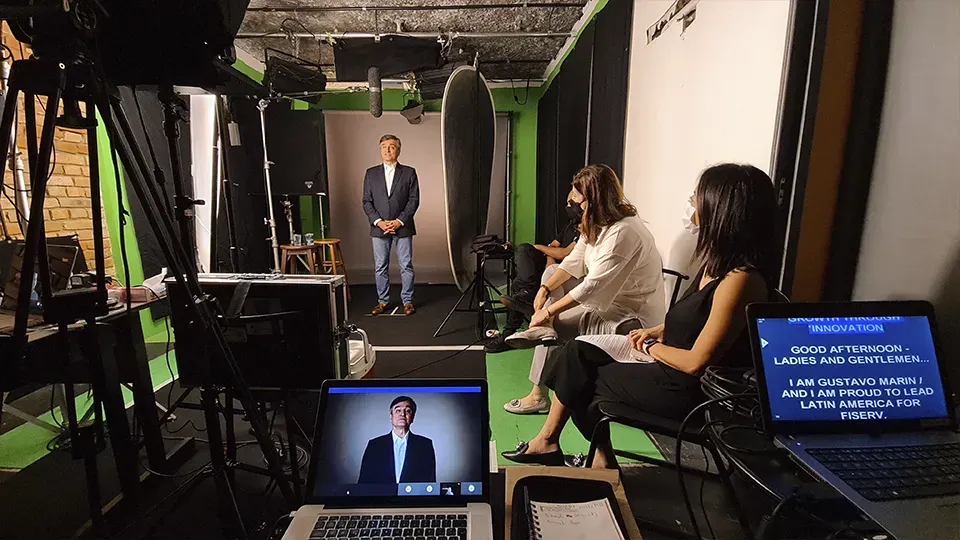A group of people are sitting in front of a green screen in a studio.