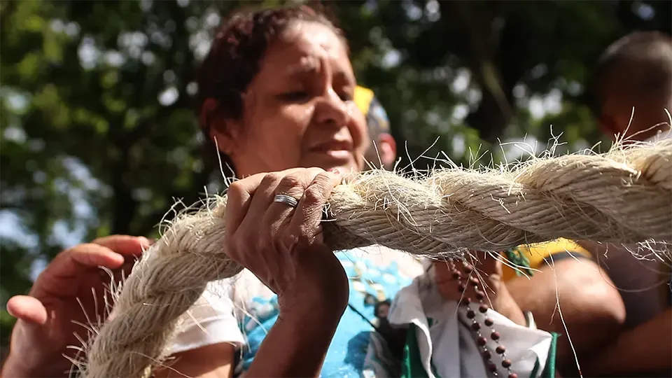 A woman is holding a large piece of rope.