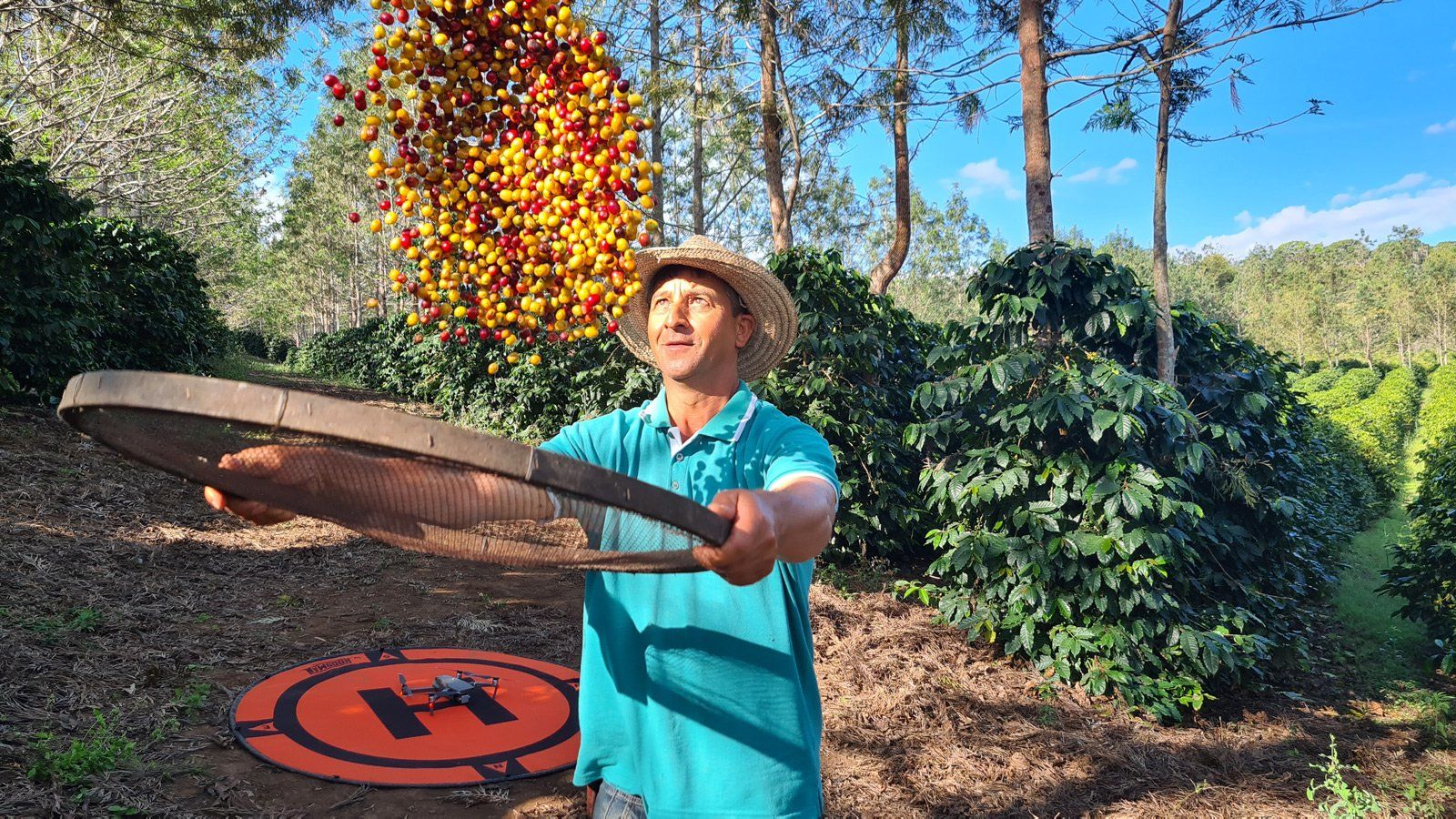 A man in a hat is holding a wooden tray in a field.