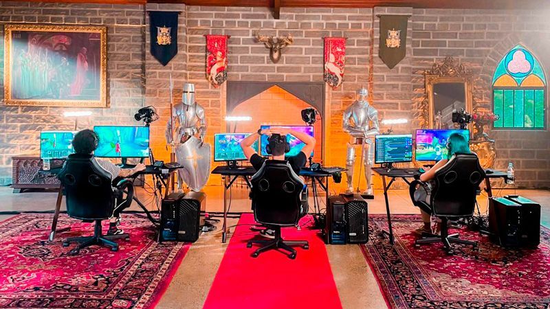 A group of people are sitting at desks in a room with a red carpet.