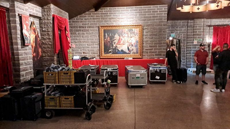 A group of people are standing in a room with a painting on the wall.