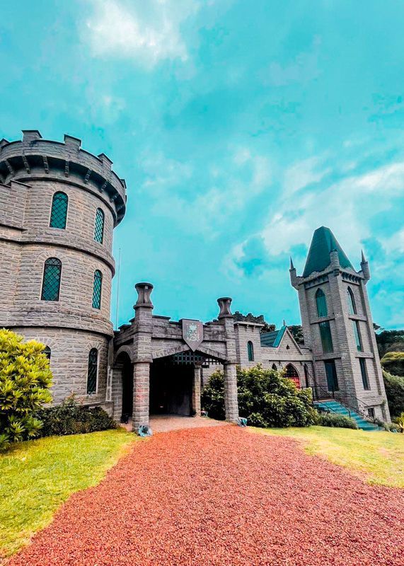 A large castle with a red gravel driveway leading to it.