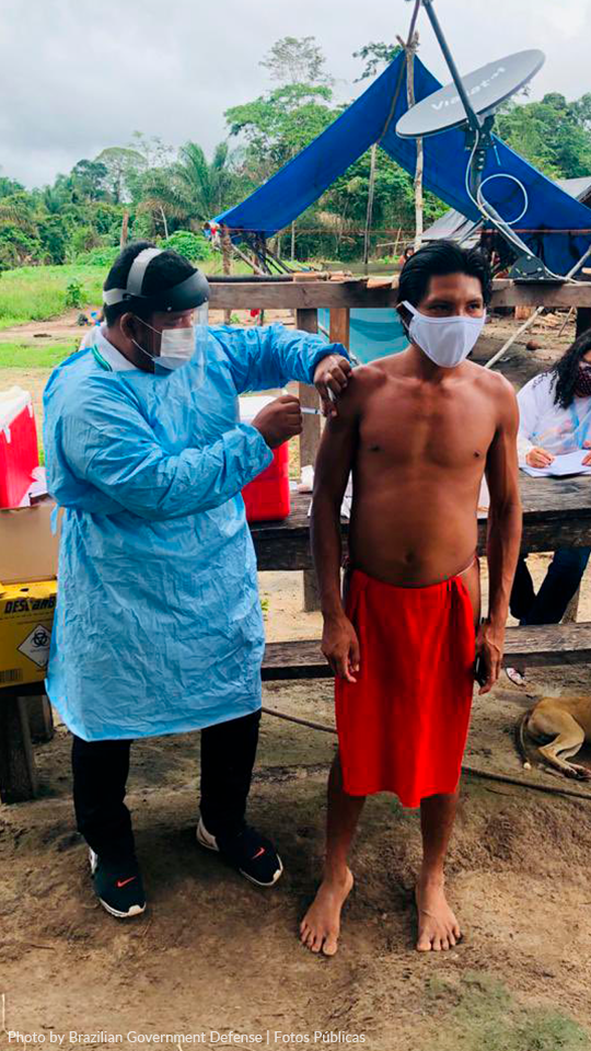 Vaccination at the Mukuru village - Waiapi Indigenous Land, Amapá A shirtless man in red shorts is getting a vaccine from a doctor.