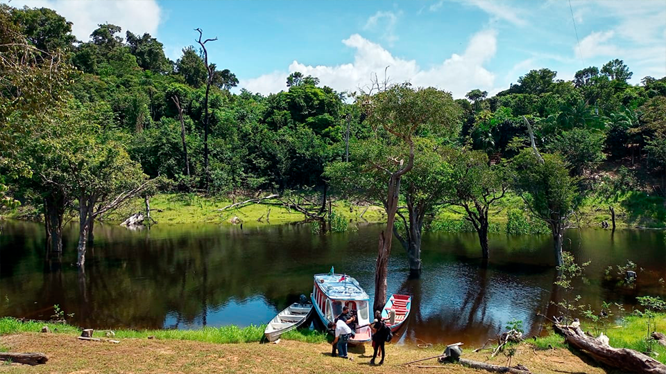 A boat is docked on the shore of a lake surrounded by trees.
