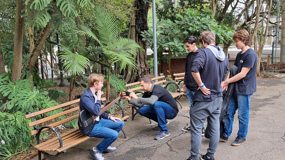 A group of young men are standing around a park bench.