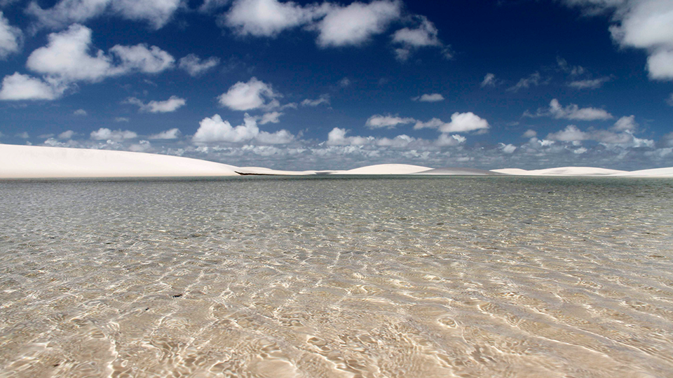 A large body of water with a blue sky in the background