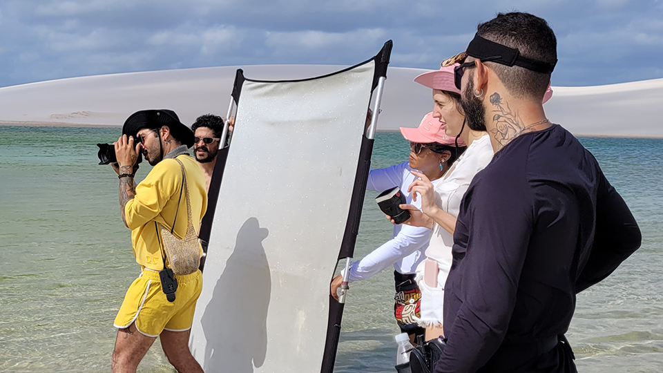 A group of people are standing on a beach taking pictures.