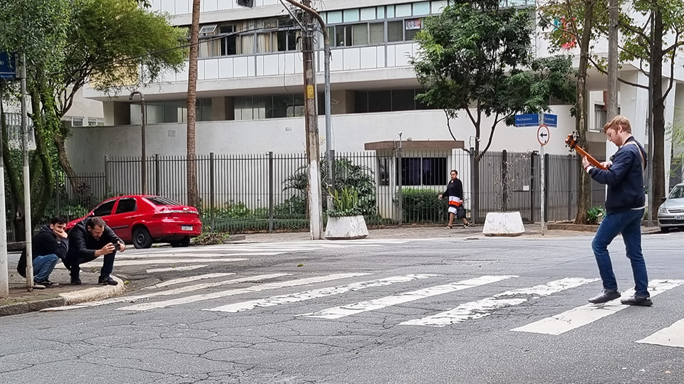 A man is playing a guitar while another man takes a picture of him.
