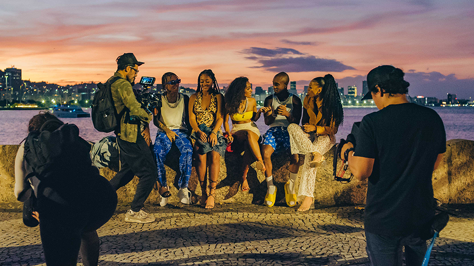A man is taking a picture of a group of people sitting on a wall.