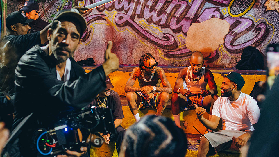 A group of men are sitting on a bench in front of a graffiti wall.