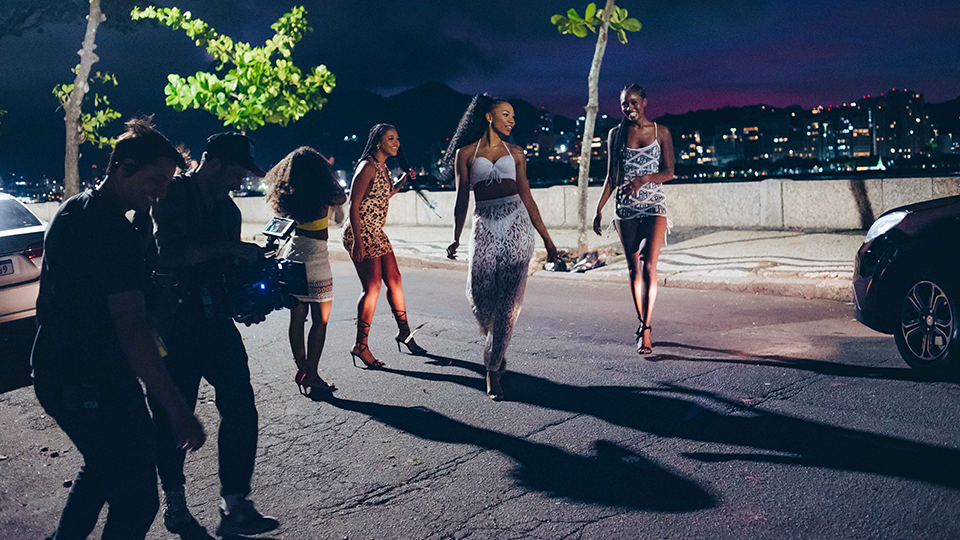 A group of women are walking down a street at night.
