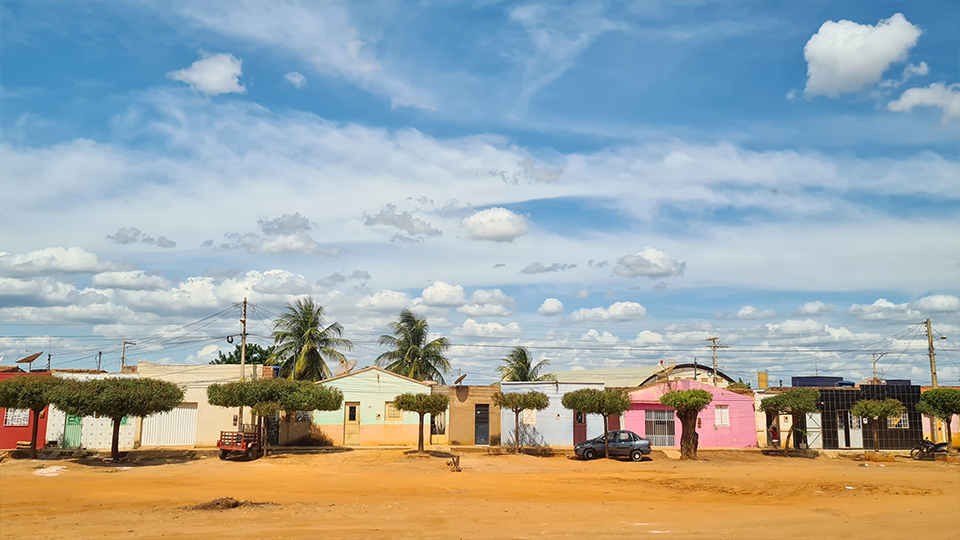 Story Productions films on location in Bahia, northern state of Brazil A row of houses with palm trees in front of them under a cloudy sky.