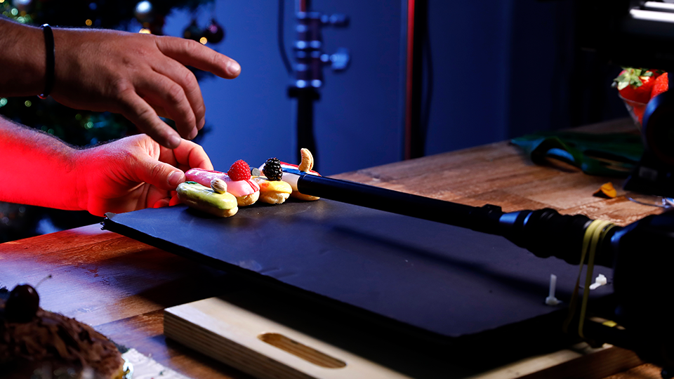 A person is cutting a piece of cake on a cutting board.