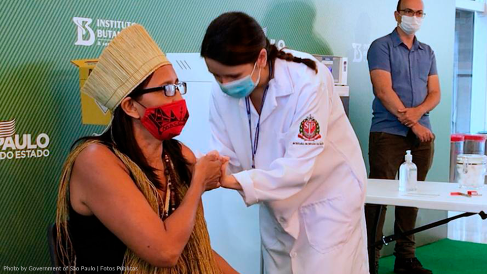 A woman wearing a mask is getting a vaccine from a doctor.