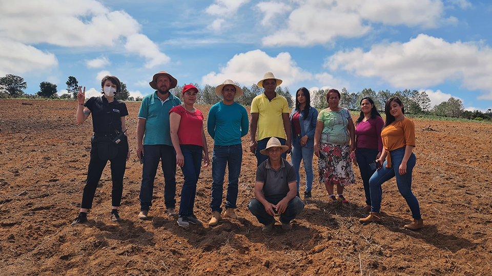 Trabajadores agrícolas junto con el equipo de Story Productions A group of people are posing for a picture in a dirt field.