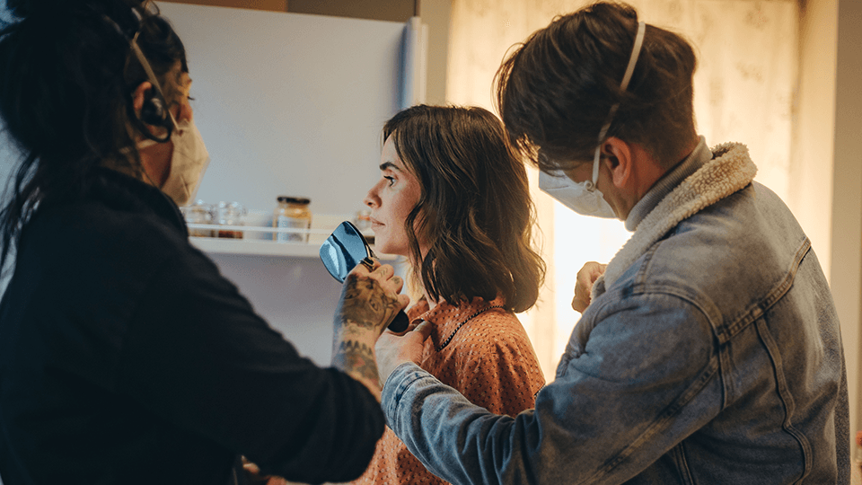 A man wearing a mask is taking a picture of a woman 's face.