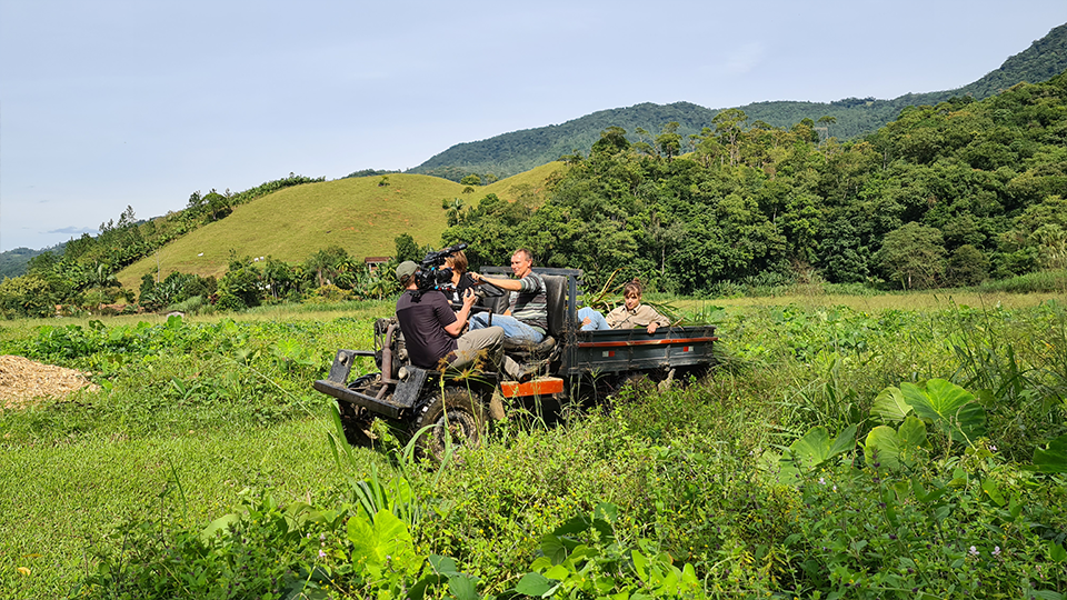 A group of people are sitting on the back of a truck in a field.