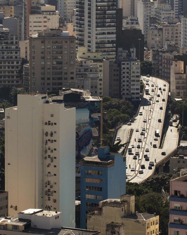 An aerial view of a city at night with a sunset in the background.