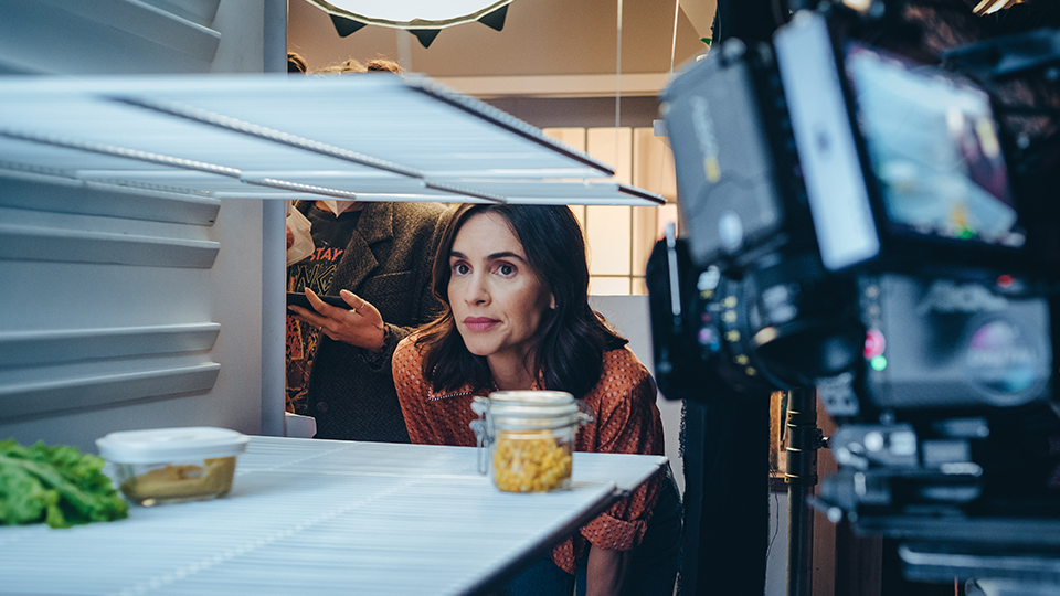 A woman is looking into an empty refrigerator.