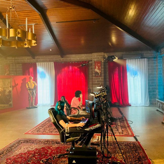 A group of people are sitting in a room with red curtains