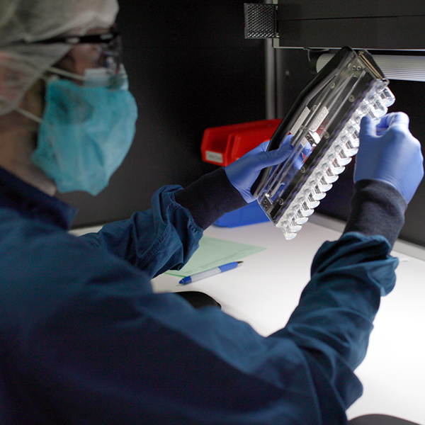 A person wearing a mask and gloves is working on a device