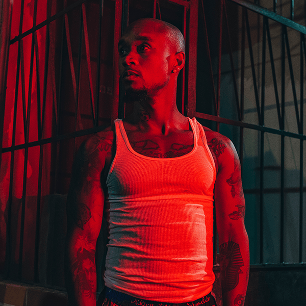 A man in a tank top is standing in front of a red light.